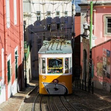 A yellow tram on a steep street in Lisbon